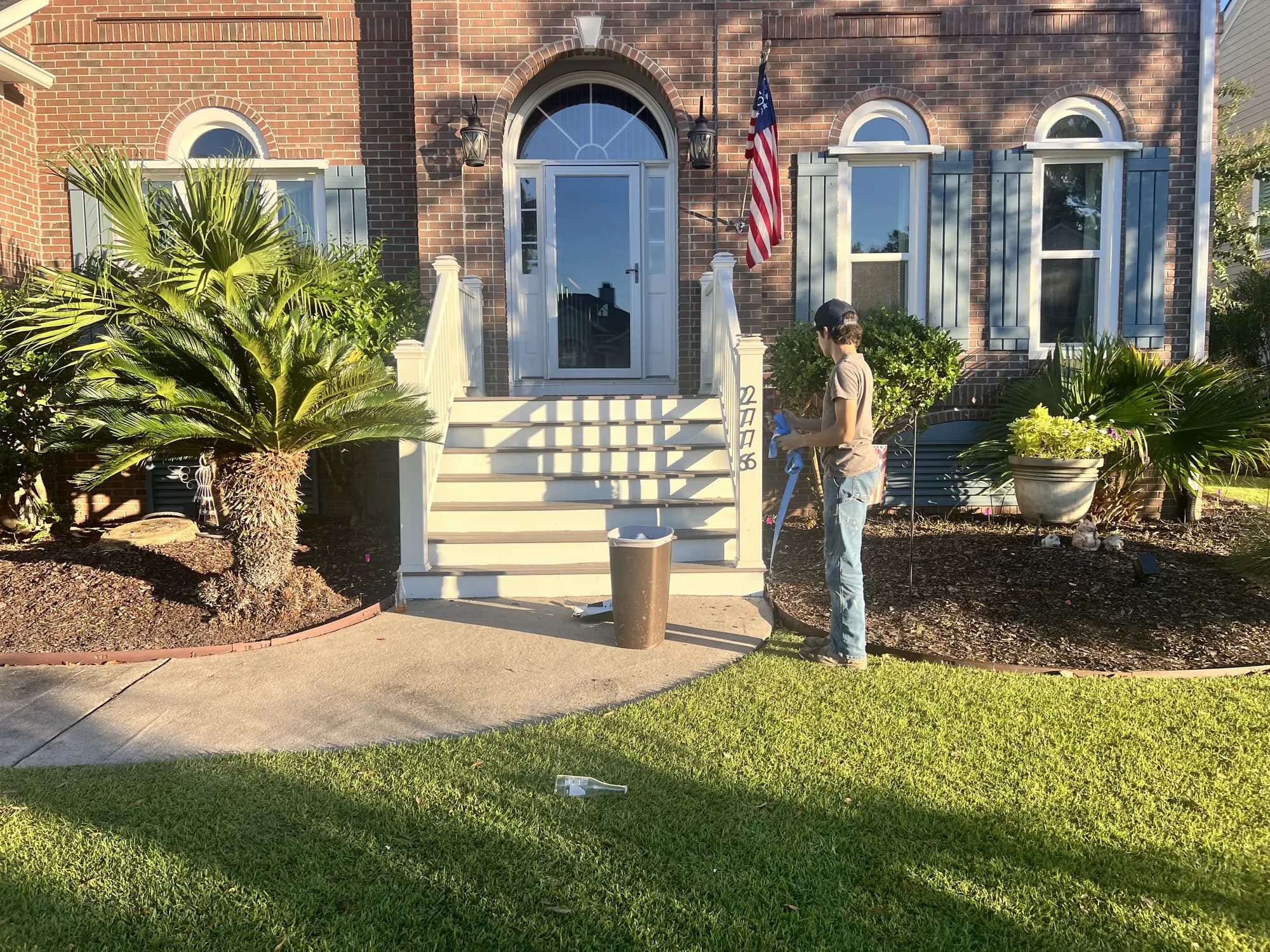 Crew member finishing fresh mulch beds at a brick home's front entry
