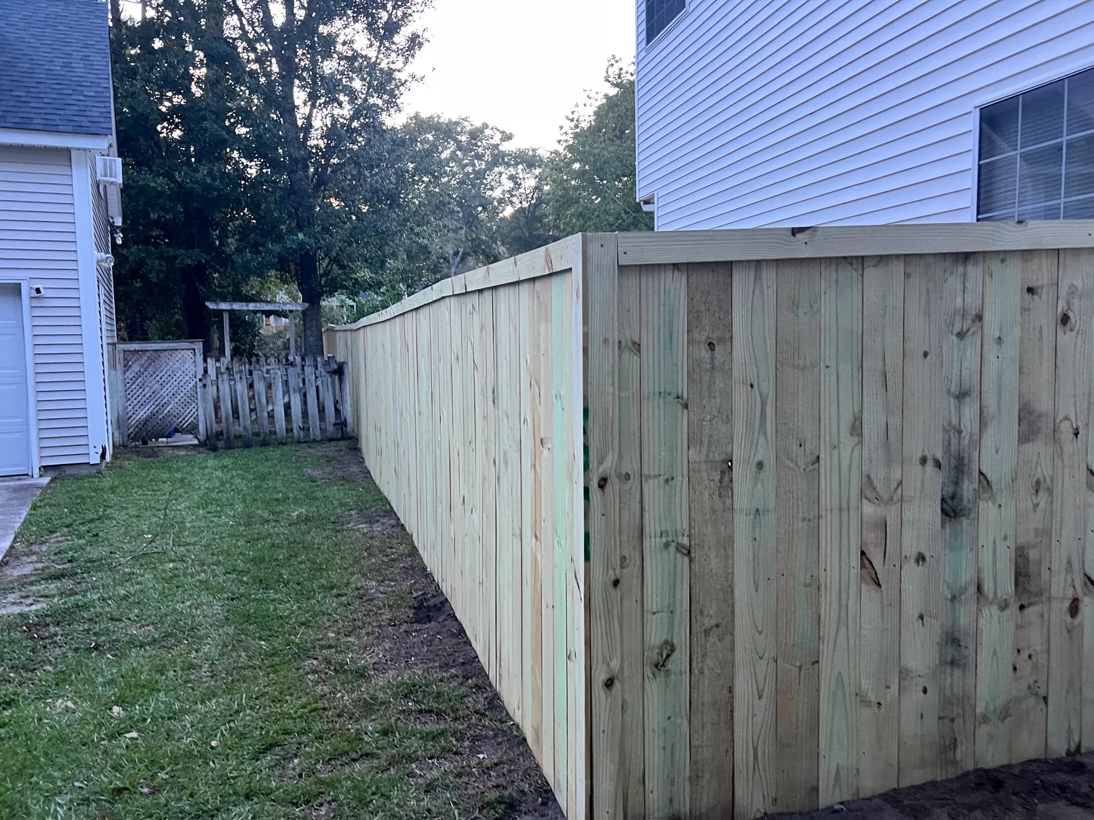Capped wood privacy fence turning a corner beside a home